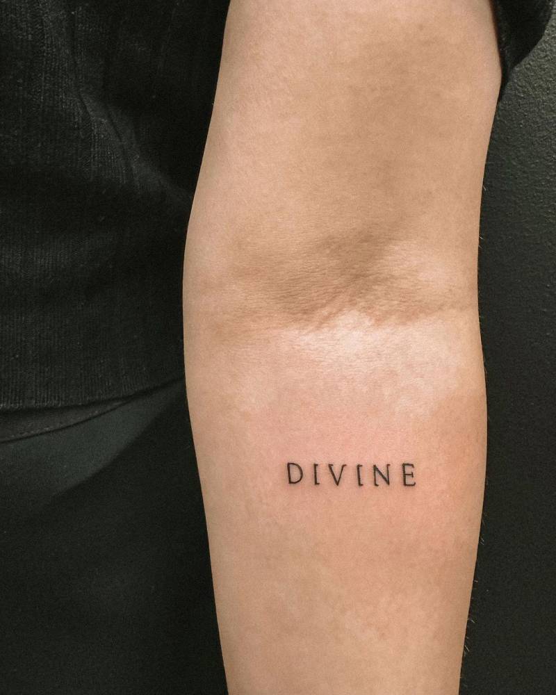 Tattoo Of The Word Divine Located On The Inner